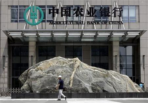 A pedestrian walks past a logo of Agricultural Bank of China in front of its headquarters in Beijing.