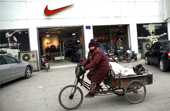 A woman rides past a clothing store at the business area of Jiaozuo, China's central Henan province.
