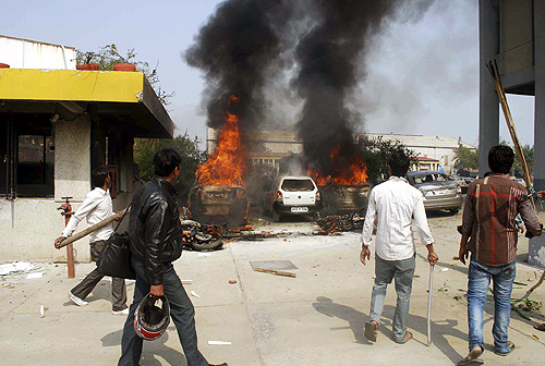 Protesters stand after they set vehicles on fire during a strike in Noida, on the outskirts of New Delhi.