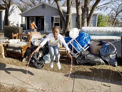 A young girl jumps rope on the sidewalk next to her family's belongings after she, her parents, and her four brothers and sisters, received a court order of eviction due to foreclosure, in Waco, Texas.