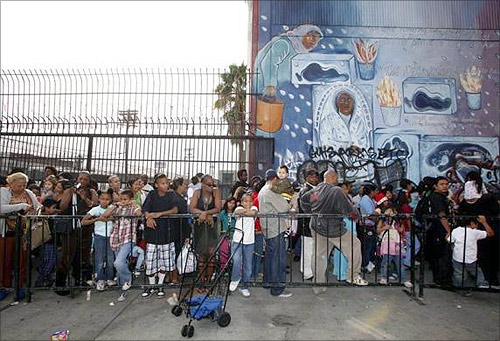 People wait in line at the Fred Jordan Mission to be one of the approximately 10,000 underprivileged children and families to receive new toys, warm clothes, blankets and Christmas dinner food bags at Fred Jordan Mission's 66th annual Family Christmas Celebration and Toy Party in Los Angeles.