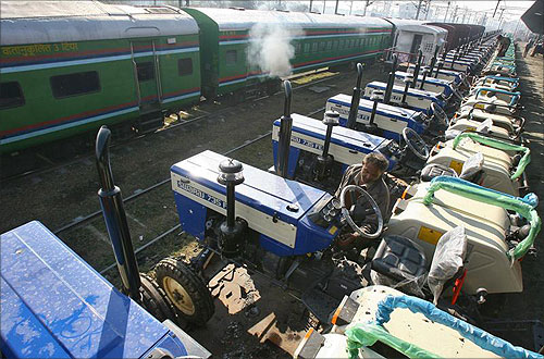 A worker checks a tractor loaded on a goods train at a railway yard in the northern Indian city of Chandigarh.