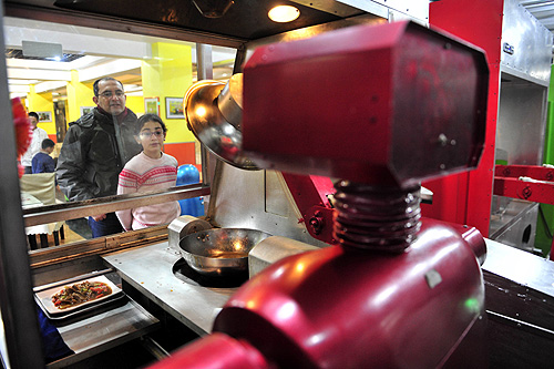 Customers watch a robot cooking dishes at a Robot Restaurant in Harbin, Heilongjiang province.