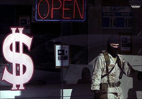 A soldier stands inside a raided pawn shop while under investigation for money laundering in Tijuana.
