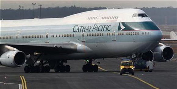 An airport apron controller vehicle is pictured in front of a Cathay Pacific Boeing B747-400 Aircraft on the runway at Frankfurt's airport.
