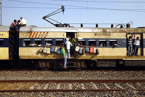 Homemade alcohol containers hang from a train window as people hang from the doors and windows at Parsha Bazar railway station in Bihar.
