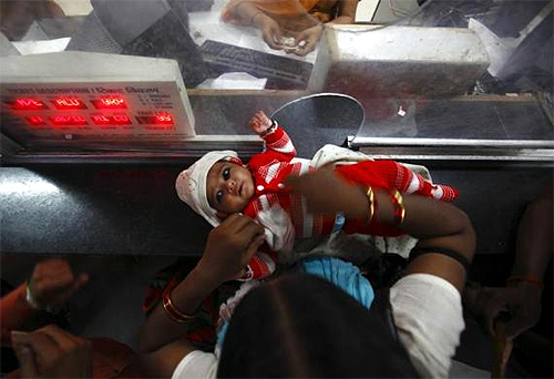 A woman keeps her child on the ticket counter as she buys a train ticket at Allahabad railway station.