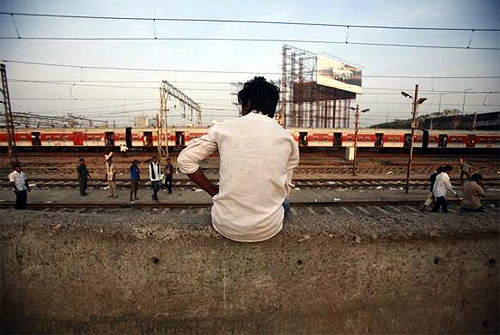 A man sits on a wall near the tracks of Bandra Railway station in Mumbai.