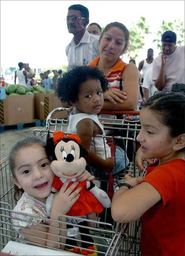 Samantha Cerda (L), 3, holds up her Minnie Mouse as she, Tatiana Jackson (C), Tabihta Cerda (R), and Juanita Valdez (middle rear) wait in line at the HEB Gulfgate Grocery store in Houston, Texas.