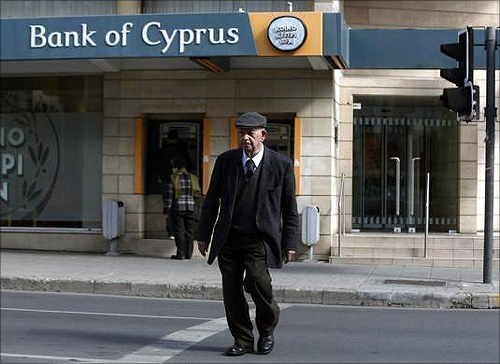 An elderly man crosses the street in front of a branch of the Bank of Cyprus in Nicosia.