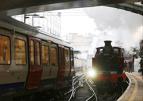 A steam train passes a tube train as it enters Farringdon Station in London.