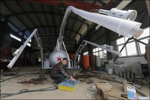 Zhang Wuyi looks up as he squats under a suction pipe of his new submarine that captures sea cucumbers at his workshop in Wuhan, Hubei province.