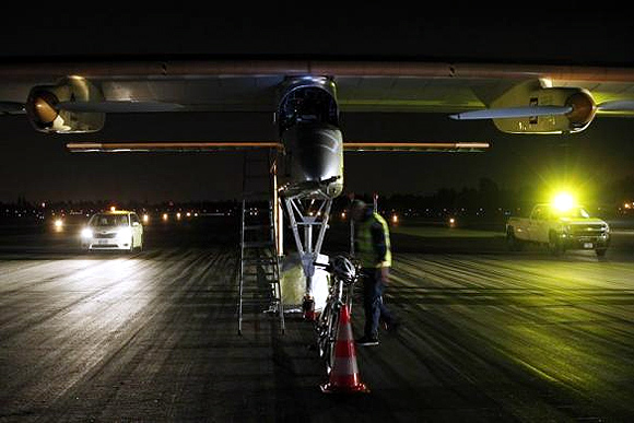 A Solar Impulse crew member walks in front of a sun-powered aircraft at Moffett Field before the first leg of its 2013 Across America Mission, piloted by Bertrand Piccard, in Mountain View, California.