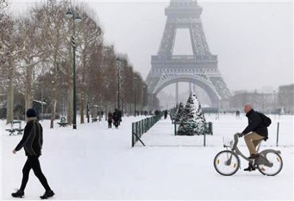 A man rides a Velib self-service public bicycle as he makes his way along a snow-covered area at the Champs de Mars near the Eiffel Tower in Paris.
