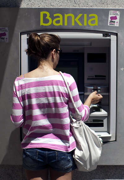 A woman uses a Bankia bank automated teller machine (ATM).