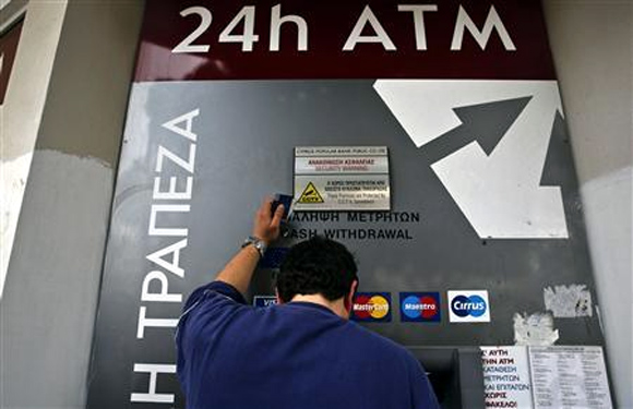 A man makes a transaction at an ATM outside a branch of Laiki Bank in Nicosia.