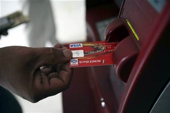 A customer uses his card to withdraw money from an ATM in Jammu.