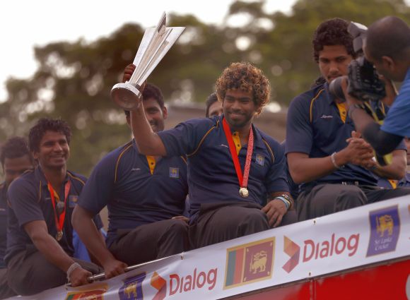 Sri Lanka's Twenty20 cricket captain Lasith Malinga (2nd R) shows the 2014 T20 trophy after they arrived at the Bandaranaike International Airport 