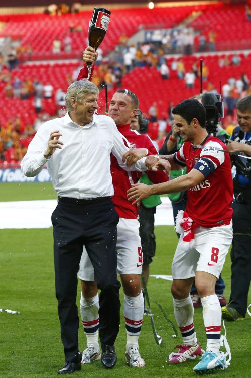 Arsenal manager Arsene Wenger (L), is covered in champagne by his players Lukas Podolski (C) and Mikel Arteta as they celebrate their victory against Hull City in the FA Cup final