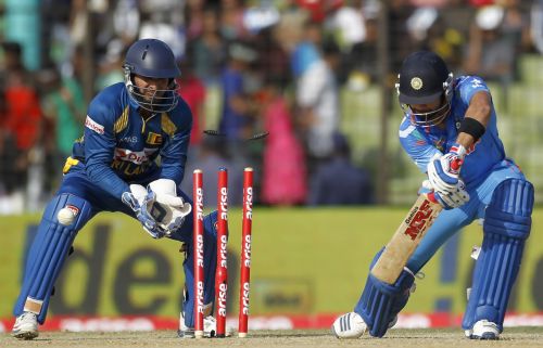 Virat Kohli is bowled out as Sri Lanka's wicketkeeper Kumar Sangakkara (L) watches on