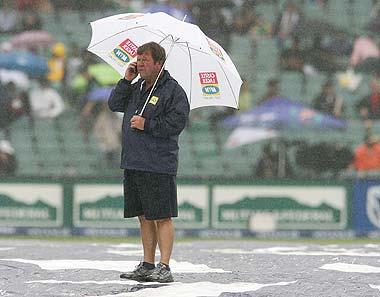 The curator of the Liberty Life Wanderers Stadium supervises the ground as the rains come down