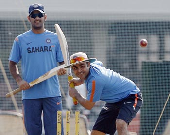 India's Virender Sehwag bats at the nets as team captain MS Dhoni watches during a training session in Mumbai