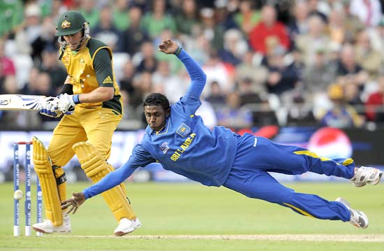 Ajantha Mendis tries to stop the ball as Mike Hussey looks on