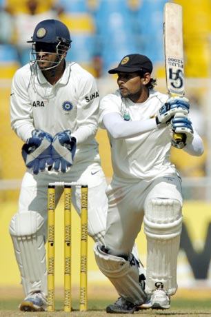Sri Lanka's Dilshan plays shot as India's captain Dhoni watches during the first test cricket match in Ahmedabad