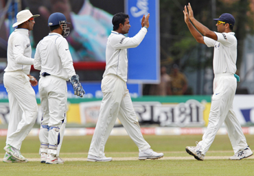 India's Pragyan Ojha (2nd R) celebrates taking the wicket of Sri Lanka's captain Kumar Sangakkara with teammate Rahul Dravid