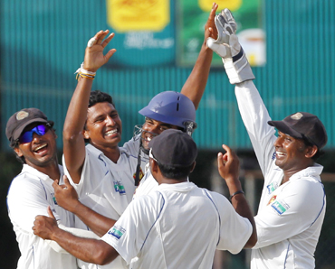 Sri Lanka's Suraj Randiv (2nd L) is congratulated by his teammates after he took the wicket of India's Rahul Dravid