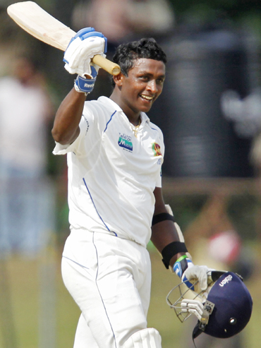 Sri Lanka's Ajantha Mendis raises his bat to celebrate scoring his half century against India