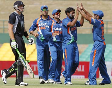 Praveen Kumar (2nd right) celebrates with his teammates after taking the wicket of Martin Guptill (left)
