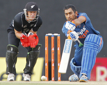India's captain Mahendra Singh Dhoni (R) plays a shot as New Zealand's wicketkeeper Gareth Hopkins