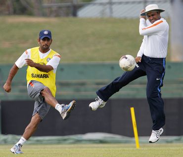 India captain M S Dhoni kicks a soccer ball past Sehwag during practice