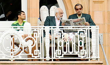 Pakistan's Manager Yawar Saeed (right) and assistant manager Shafqat Ranan (centre) read the News of the World newspaper as Kamran Akmal looks on