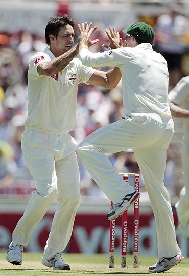 Australia's Mitchell Johnson (left) and Michael Hussey celebrate the dismissal of England's Jonathan Trott