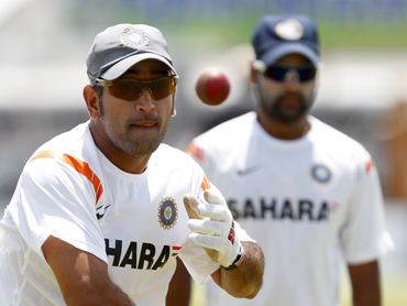 India's captain Dhoni throws a ball as Mishra watches during a practice session in Galle