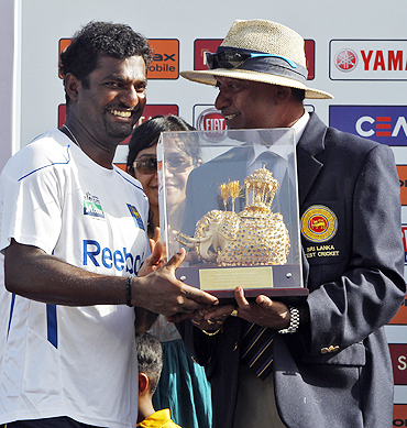 Galle curator Jayananda Warnaweera presents a momento to Muralitharan (left) to mark his retirement from Test cricket