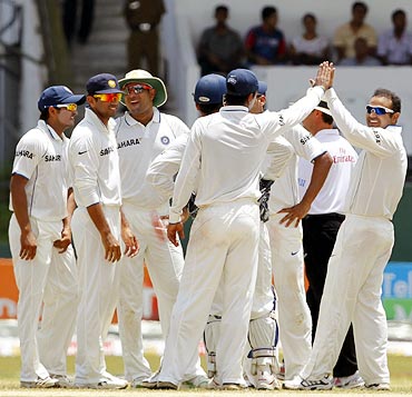 Virender Sehwag (right) celebrates with team mates after taking the wicket of Kumar Sangakkara