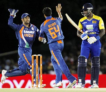 Mahendra Singh Dhoni (left) congratulates Ashish Nehra after he took the wicket of Angelo Mathews