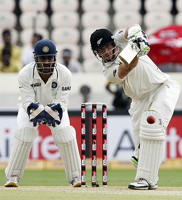 New Zealand's Martin Guptill plays a shot as MS Dhoni watches