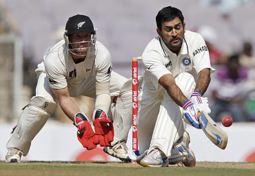 Mahendra Singh Dhoni plays the sweep shot as New Zealand's wicketkeeper Gareth Hopkins looks on