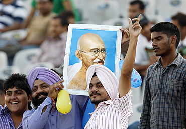 Indian fans hold up a portrait of Mahatma Gandhi and sing in the stands on the occassion of Gandhi Jayanti in Mohali on Saturday