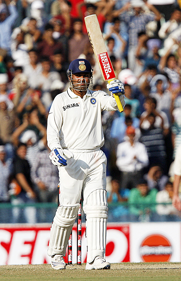 Virender Sehwag raises his bat to the pavilion after scoring 50
