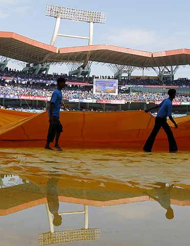 Grounds staff remove covers at Kochi stadium