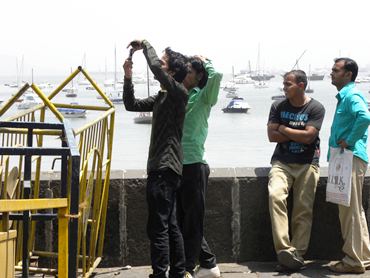 Tourists try to take a picture of the Gateway of India from afar