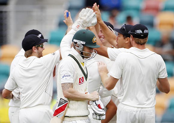 Australia's captain Michael Clarke (centre) walks past New Zealand players after losing his wicket to Doug Bracewell