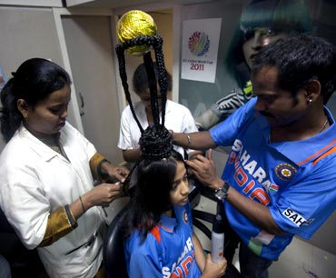 Hairdressers shape the hair of cricket fan Rajna Pandit, 22, to resemble the World Cup trophy in Mumbai