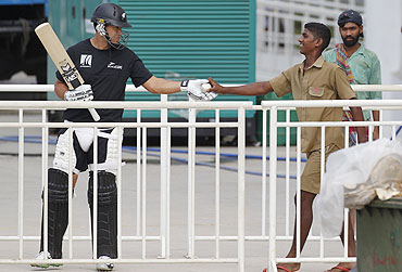 A ground worker hands over the ball to New Zealand's Rose Taylor (left) as he arrives to bat in the nets during a practice session in Chennai on Friday