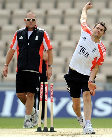 England's James Anderson bowls watched by bowling coach David Saker (L) during a training session before Thursday's third cricket